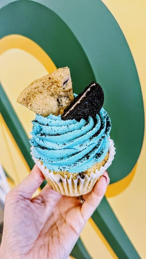 vegan cookie monster cupcake with blue buttercream frosting and half an oreo and half a chocolate chip cookie on top at strong hearts in buffalo