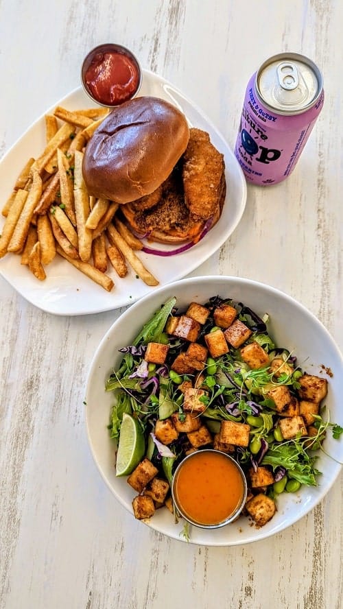 vegan chicken burger and fries and salad with thai tofu on a table at at strong hearts in buffalo