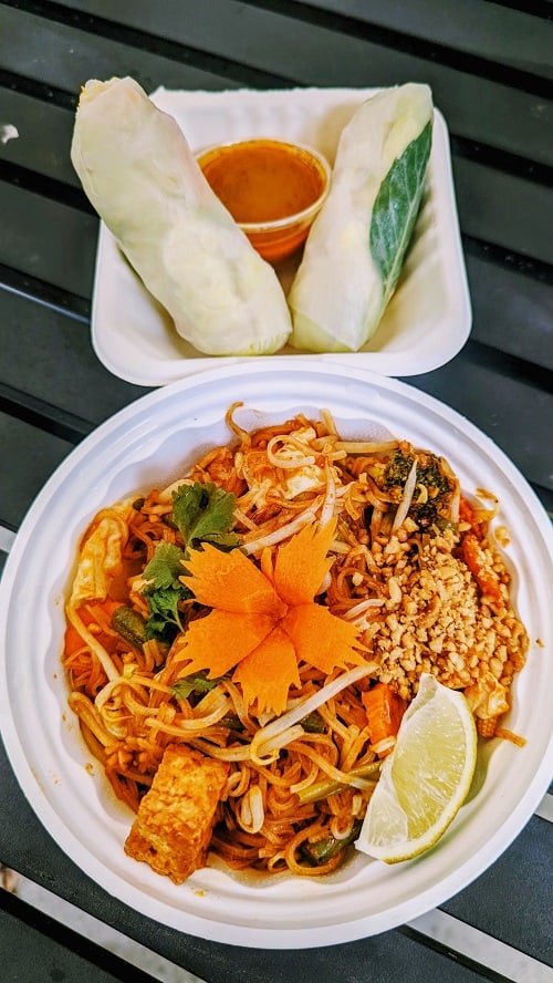 bowl of vegan pad thai with a carrot flower and line and two rainbow salad rolls from thai elephant in watkins glen finger lakes