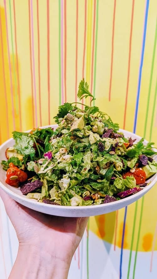 vegan chopped salad in front of a colorful wallpaper background at flower child in dc