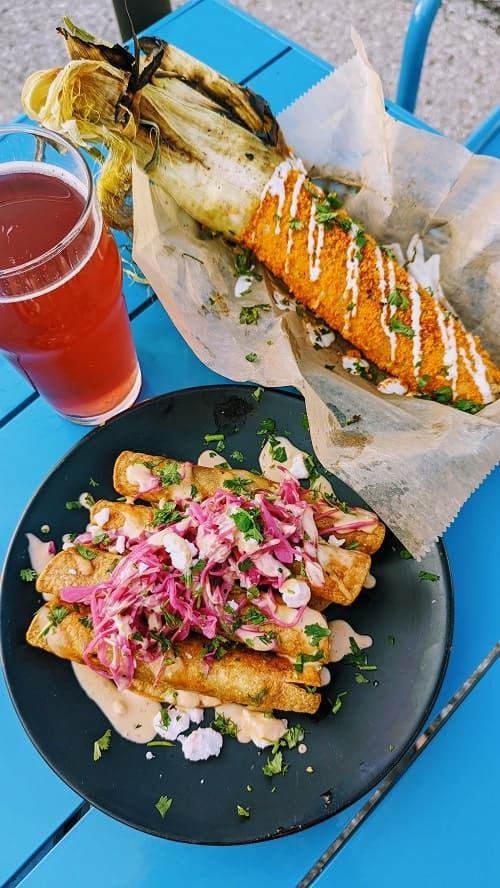 vegan taquitos covered in spicy mayo, cheese, and pickled onions and a basket with mexican elote at rad.ish street food in traverse city