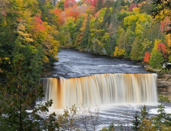 Tahquamenon Falls large waterfall surrounded by colorful fall trees in michigan