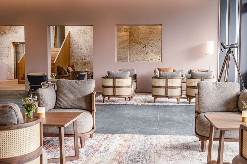 modern hotel lobby at hotel saratz with round wooden chairs, light pink walls and gray accents