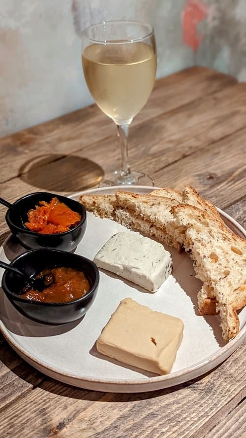 vegan cheese plate with gluten free bread and a glass of white wine at la fauxmagier in london