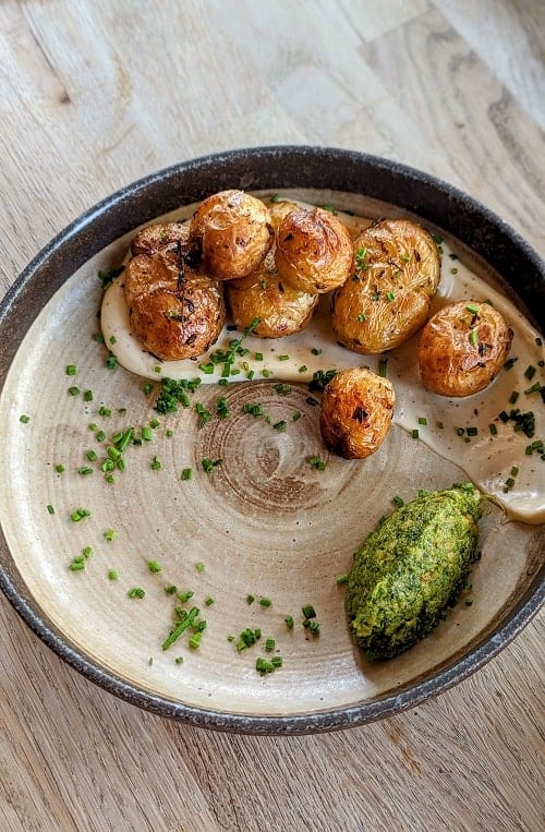 roasted potatoes in a creamy vegan cheese sauce with pesto at botanique in brighton