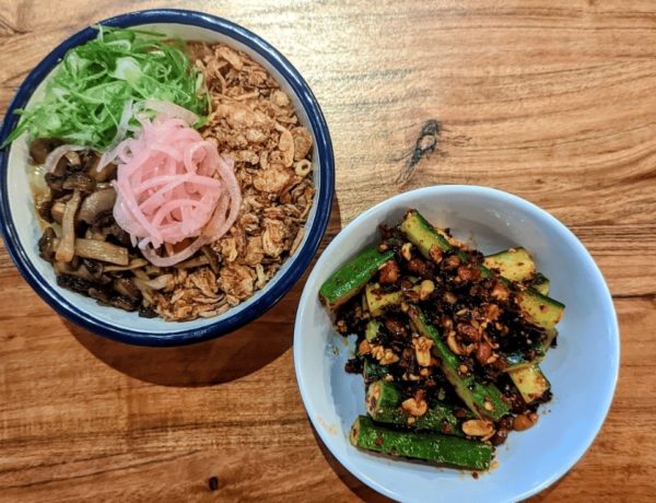 two vegan asian dishes in white bowls on a wood table at hug and pint in glasgow