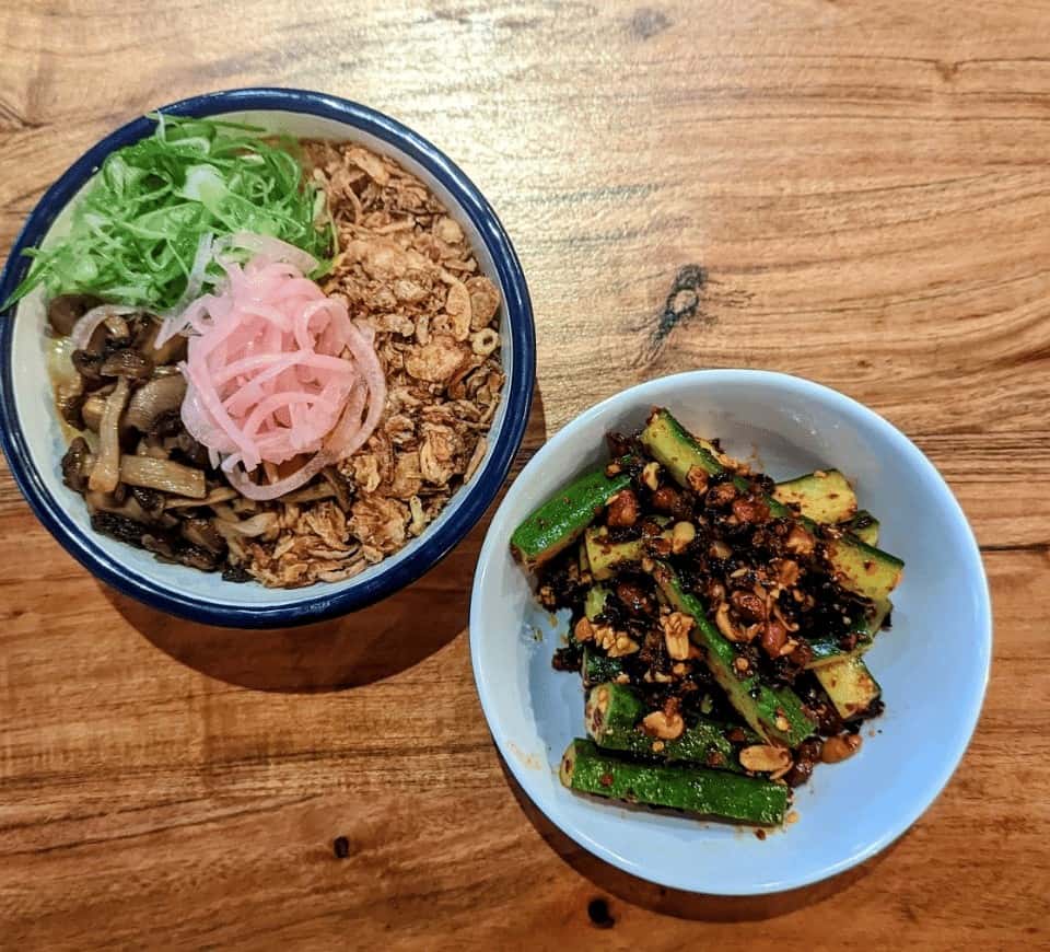 two vegan asian dishes in white bowls on a wood table at hug and pint in glasgow