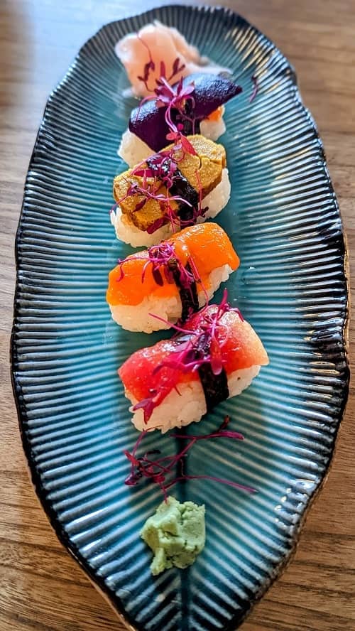 colorful vegan sushi nigiri on a blue leaf plate at kusaki in brighton
