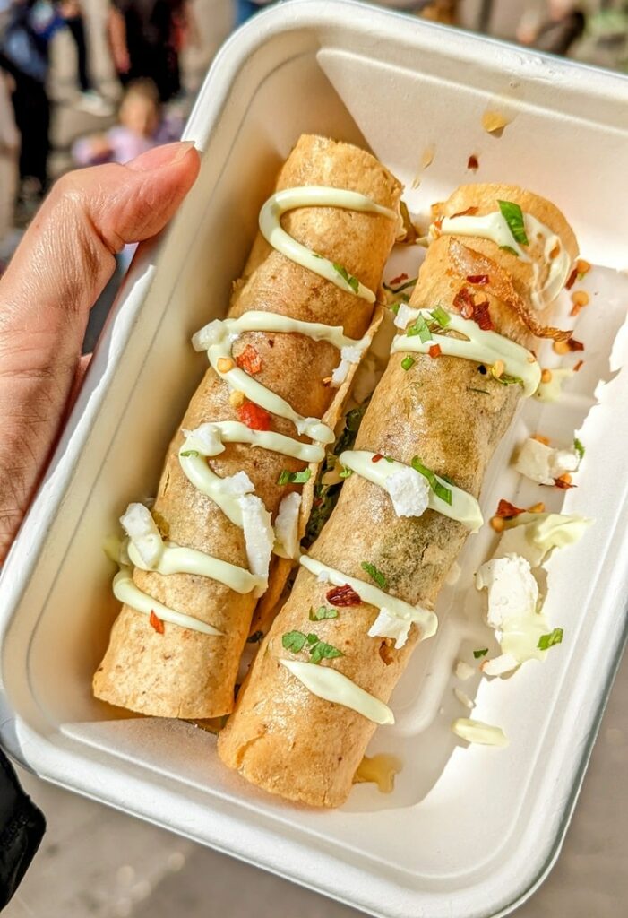 two golden crispy taquitos covered with an avocado cream sauce from antojitos in glasgow