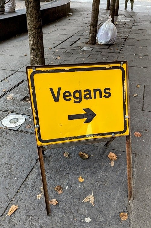 yellow directional sign showing which way vegans should head