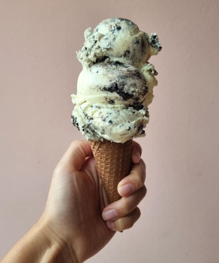 a vegan ice cream cone topped with three scoops of cookies and cream ice cream at Eisbrunnen Plant-Based Creamery in munich