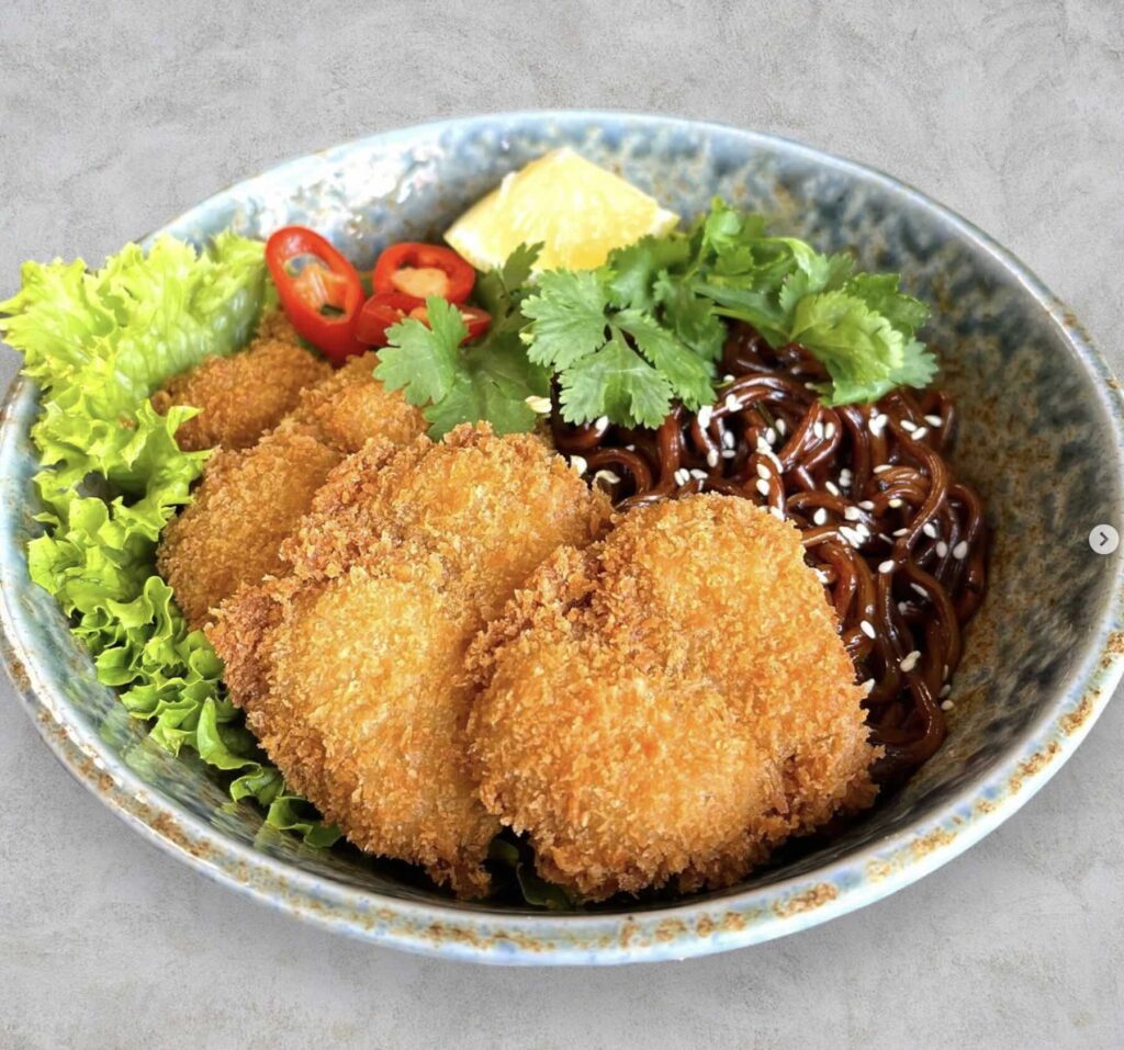 Katsu and noodle dish over bed of lettuce