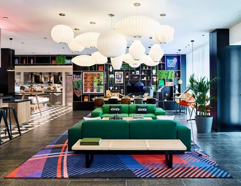 bright and colorful reception area with large hanging round white lights at citizen m in london