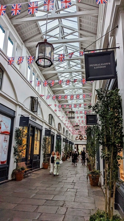 the inside of the covent garden market lined with british flags and sho[s