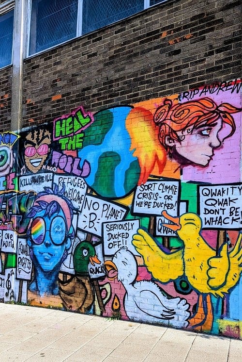 brightly colored mural with animals and people holding signs protesting climate change