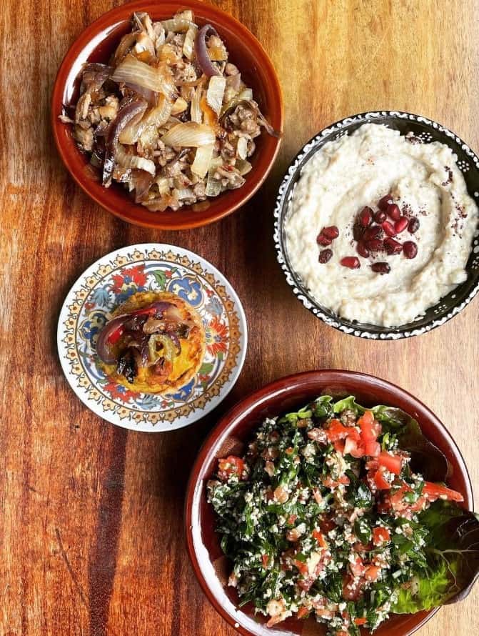 four round dishes filled with traditional middle eastern dishes like salad, garlic spread and grilled onions with lentils at hummus in edinburgh