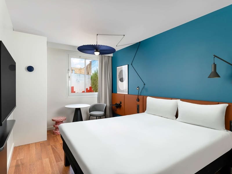 modern guestroom with a double bed with white linen and a dark blue wall at ibis budapest