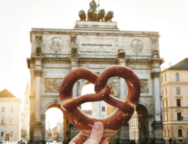 hang holding a vegan pretzel in front of munich city gate