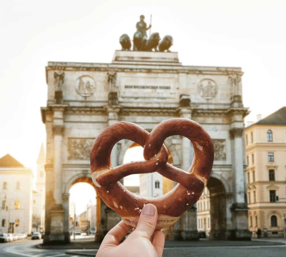 hang holding a vegan pretzel in front of munich city gate