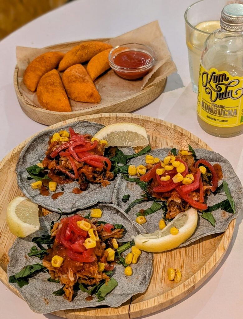 vegan jackfruit tacos next to mini golden brown empanadas with a ginger kombucha at oveja negra in madrid