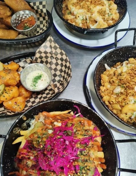 multiple dishes of vegan french fries, fried cauliflower, mac and cheese on a silver table in edinburgh
