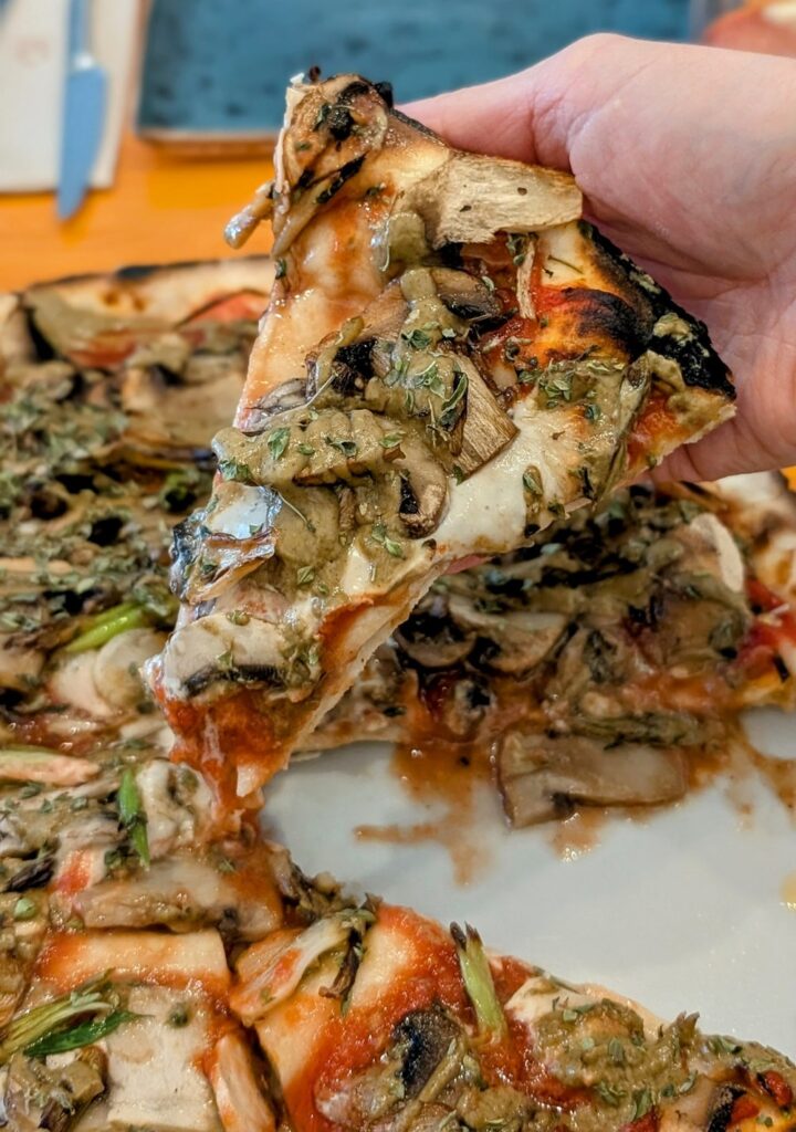 a single slice of vegan and gluten free pizza with melty cheese and cream sauce at pizzi and dixie in madrid