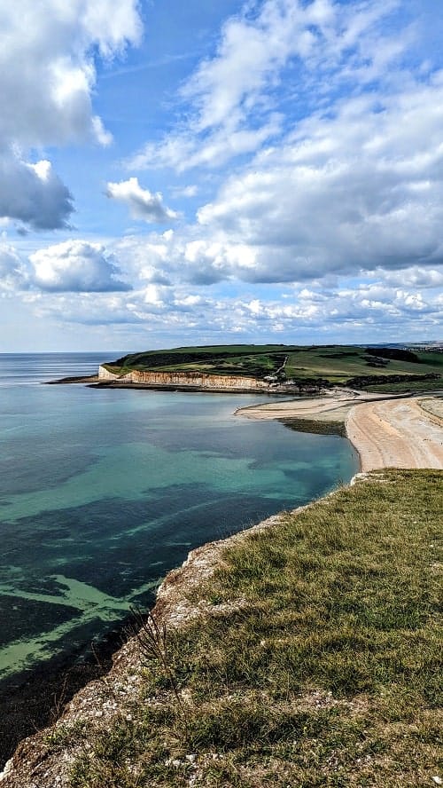 view of the english coastline with white cliffs, stone beach, and blue green water