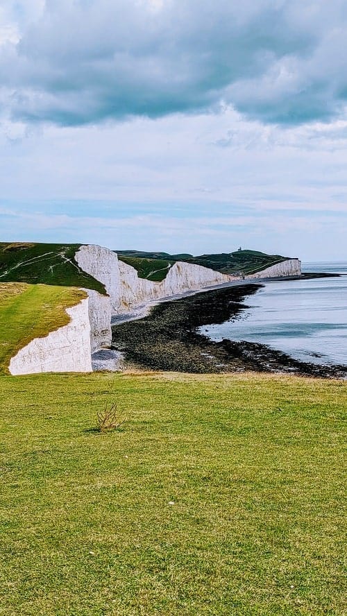 view of the giant white chalk stone cliffs called the seven sisters from a lush green hill