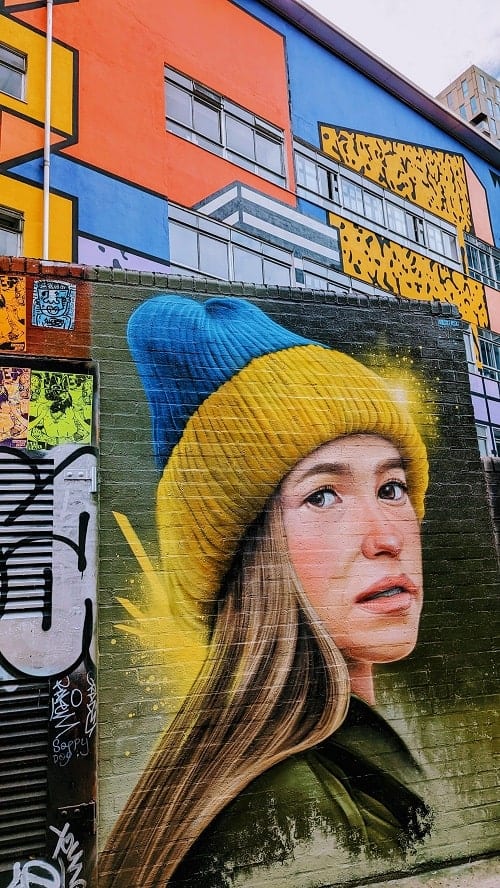 giant street mural of a young girl with a blue and yellow winter hat in shoreditch in london