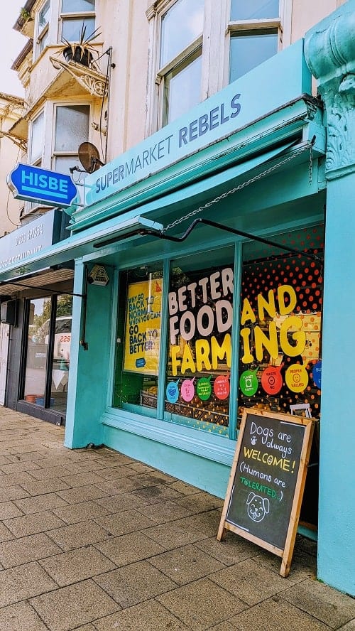 the bright light blue store front of the supermarket rebels market in brighton