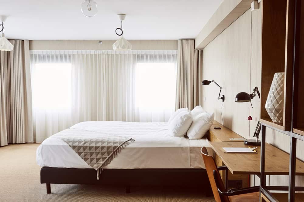 a bright and neutral colored guest room with  a large window at the vegan friendly and sustainable good hotel in london