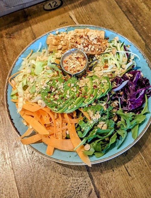 colorful veggie bowl with carrots, cabbage, zucchini, avocado, covered in a peanut sauce at seeds for the soul in edinburgh