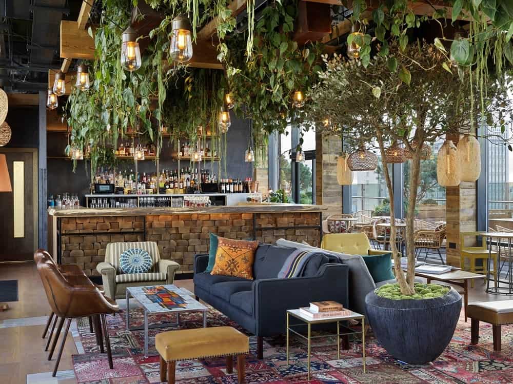 a treehouse inspired dining space with hanging leaves and branches and low lighting at the vegan friendly treehouse hotel in london