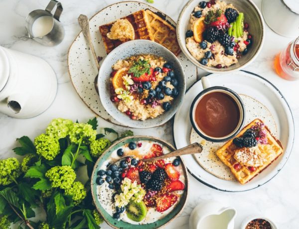 giant vegan breakfast spread with plates filled with waffles and toast and bowls filled with fruit and yogurt