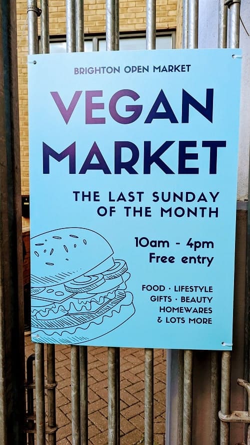 white sign with dark print promoting the vegan market in brighton