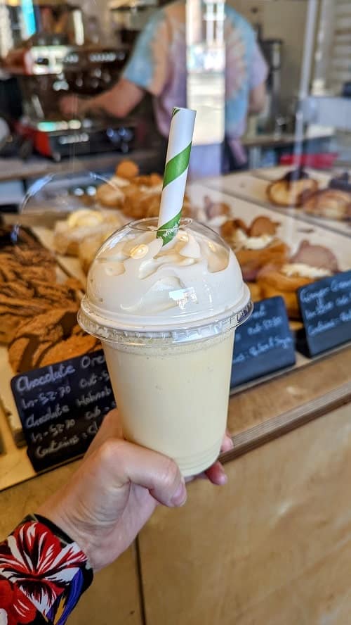 vegan passionfruit milkshake topped with coocnut whipped cream and a green stripped straw in edinburgh