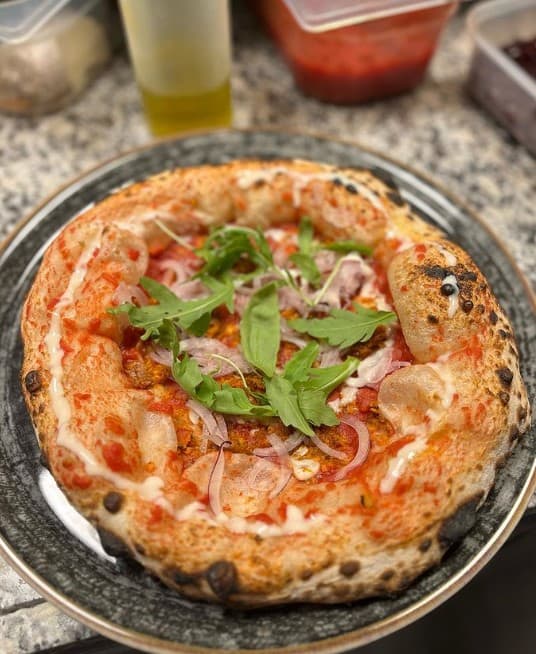 a small round vegan pizza topped with fresh basil, tomato and a cream sauce in budapest