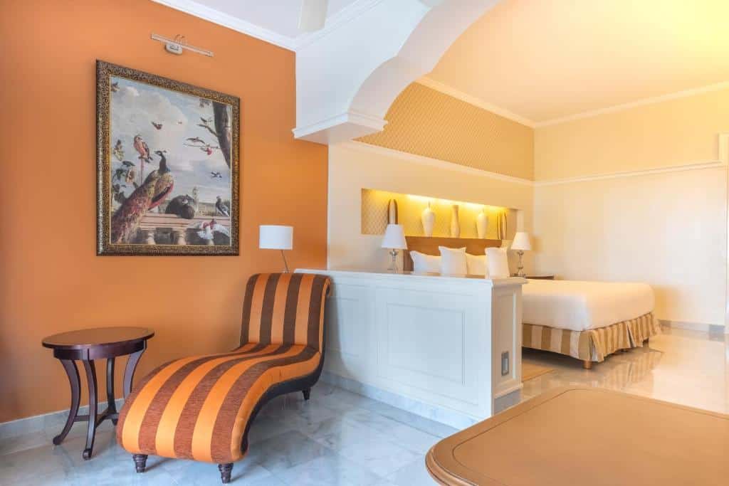 Elegant suite at JOIA Paraíso by Iberostar with a king bed, lounge chair, and warm orange accents