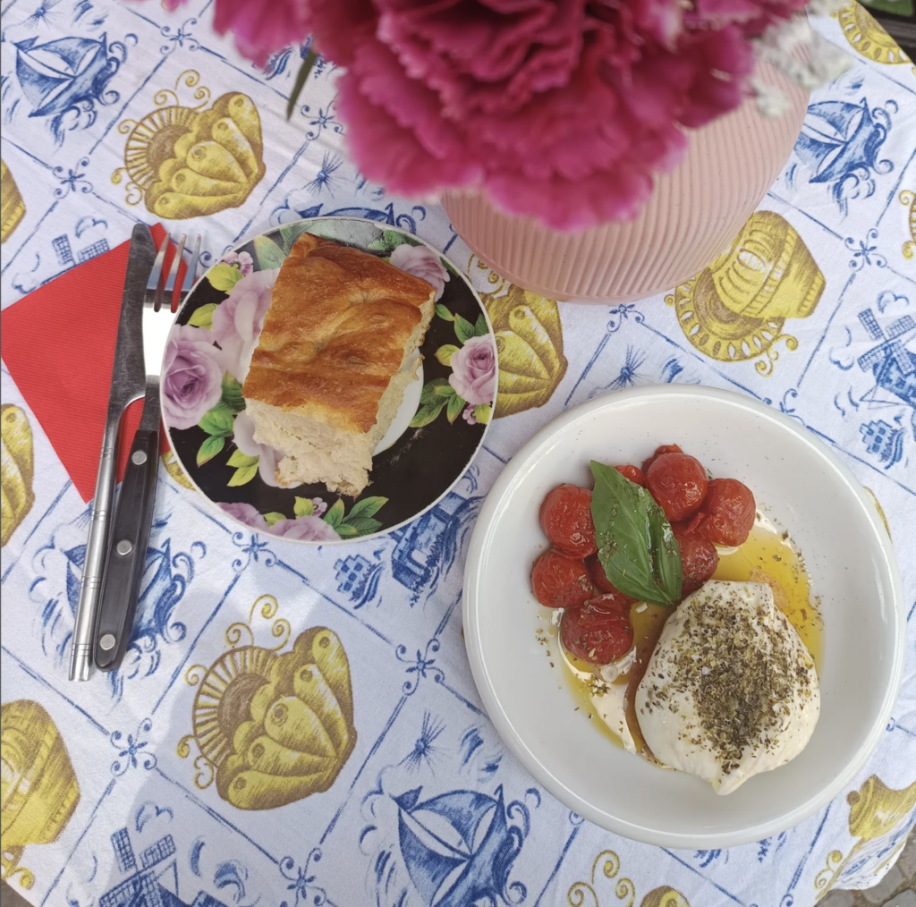 Vegan mozzarella dish at Alaska Bar Berlin served with cherry tomatoes, olive oil, herbs, and bread on a colorful table setting.