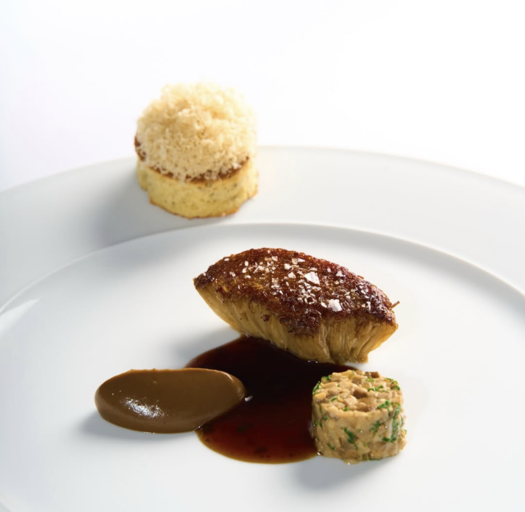 Plated enoki mushroom dish at Cookies Cream Berlin with truffle sauce, mushroom duxelles, and a vegan truffle waffle.