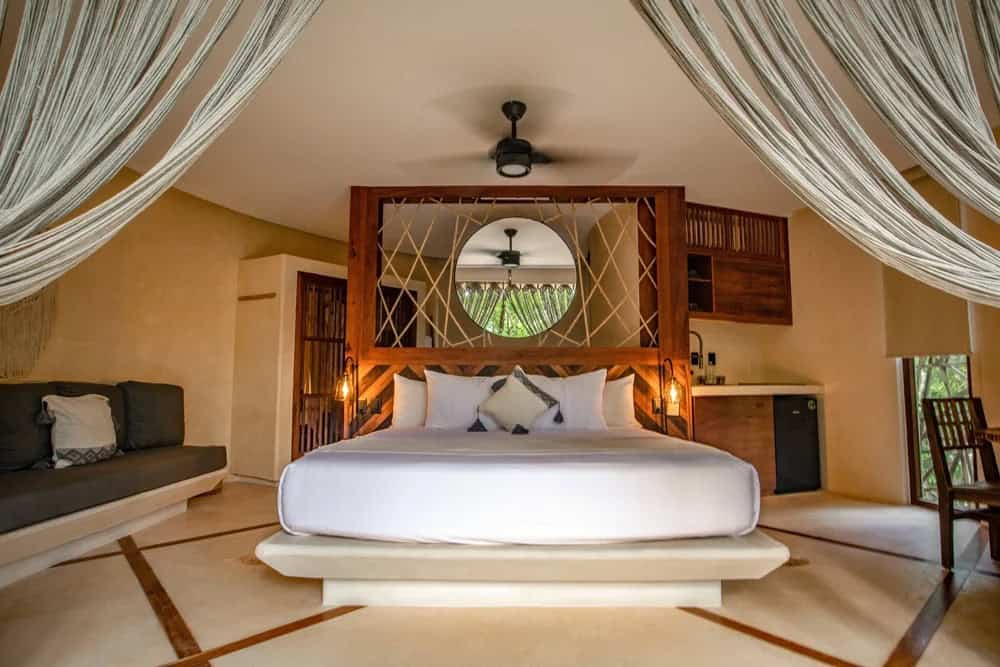 Jungle treehouse suite at KAN Tulum with a king bed, natural wood details, and draped canopy
