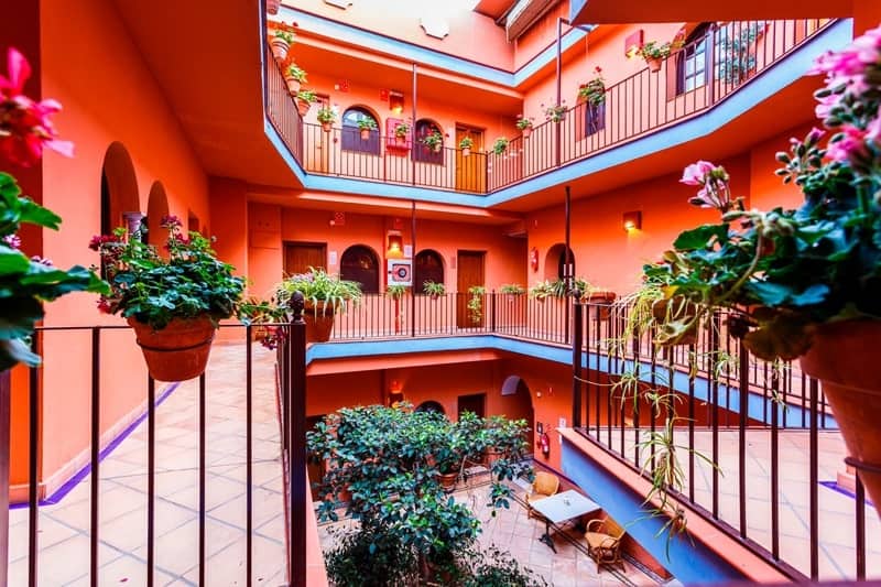 the center courtyard with red walls and a patio along the rooms at Patio De La Alameda in sevilla