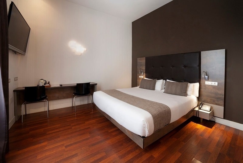 modern guestroom with dark wood floors with a queen size bed at the hotel Petit Palace Boquería Garden in barcelona