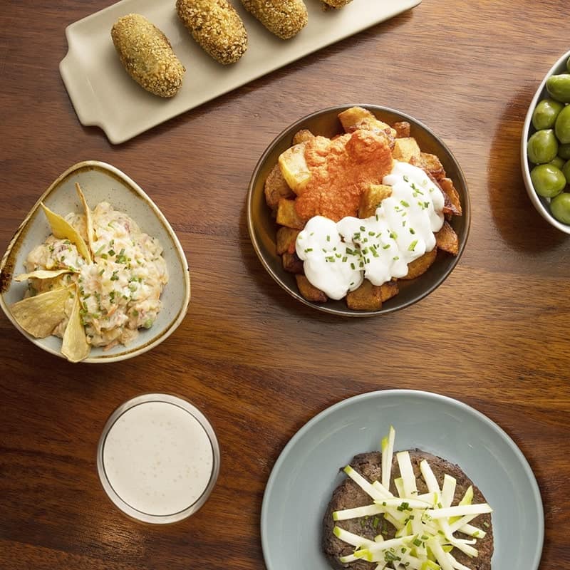 a beautiful spread of vegan and gluten free dishes on a wood table at Pötstot in barcelona