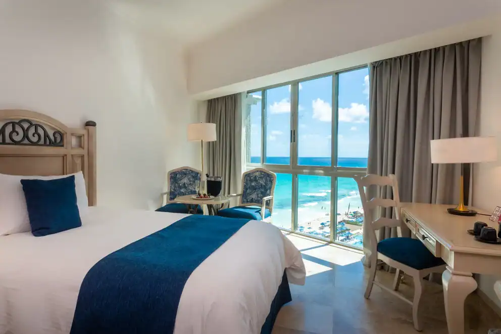 Deluxe room at Sandos Cancun with blue accents and floor-to-ceiling windows overlooking the Caribbean Sea