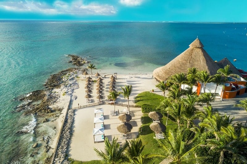 overhead shot of the white sand beach, turquoise water and palm trees at club med cancun