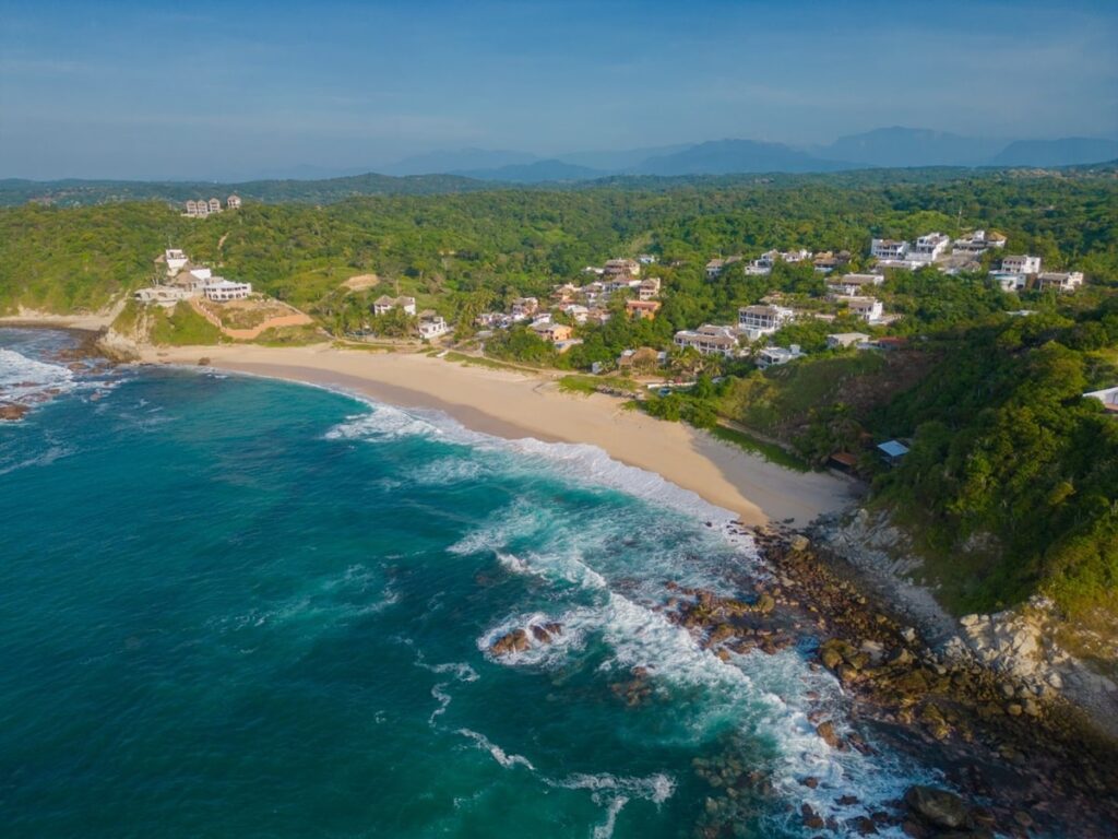 overhead view of a secluded beach surrounded by blue water just steps from the vegan hotel casa mauna in oaxaca mexico
