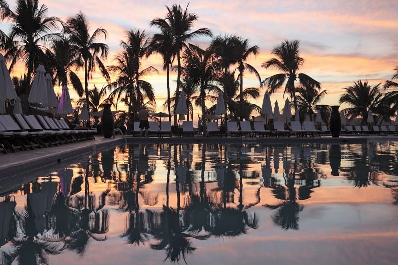 view of the pool at club med ixtapa with the light pink and orange sunset in the background