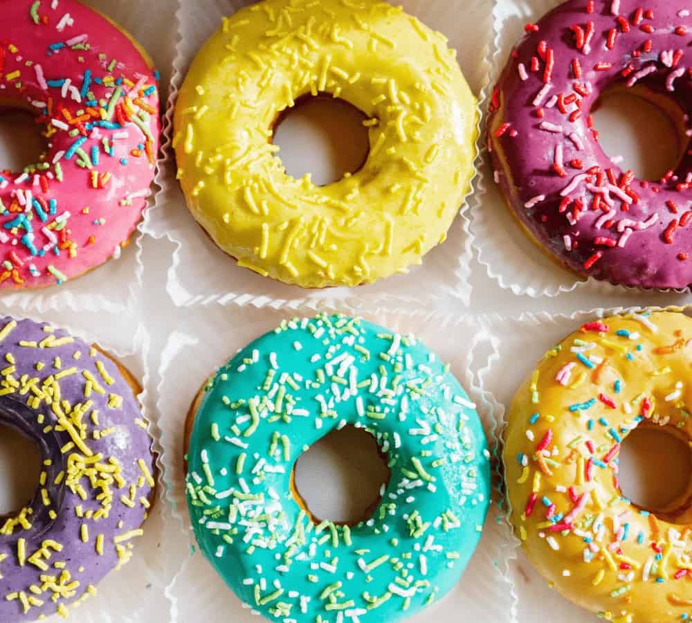 bright green, yellow, and pink cake donuts topped with colorful sprinkles