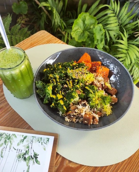 a bowl filled with a healthy mix of veggies including spinach next to a green smoothie in barcelona